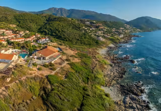 Vue aérienne du Paese Di Lava, à flanc de colline au-dessus de la côte rocheuse du golfe de Lava