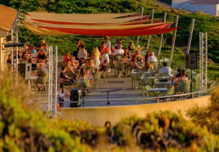 Terrasse animée au coucher du soleil, sous des voiles colorées