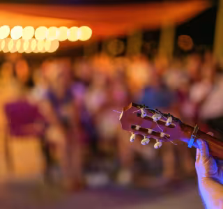 Mise au point sur un manche de guitare avec des spectateurs flous en arrière plan