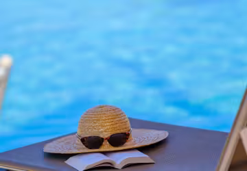 Chapeau sur un transat au bord de la piscine