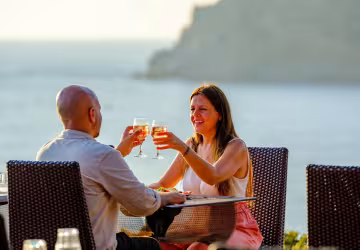 Couple trinquant sur une terrasse face à la mer