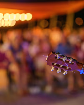 Mise au point sur un manche de guitare avec des spectateurs flous en arrière plan
