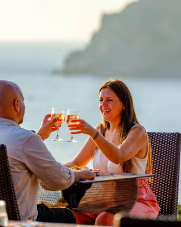 Couple trinquant sur une terrasse face à la mer