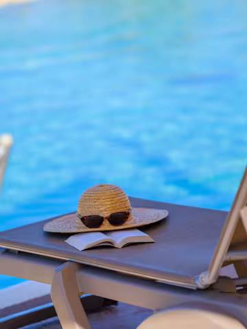 Chapeau sur un transat au bord de la piscine