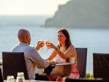 Couple trinquant sur une terrasse face à la mer