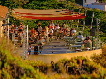 Terrasse animée au coucher du soleil, sous des voiles colorées